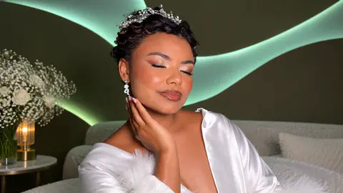 Noiva de olhos fechados, com tiara e maquiagem iluminada em tons pêssego
