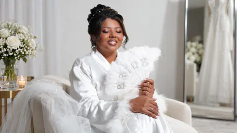 Noiva sorrindo com leque de plumas durante a preparação